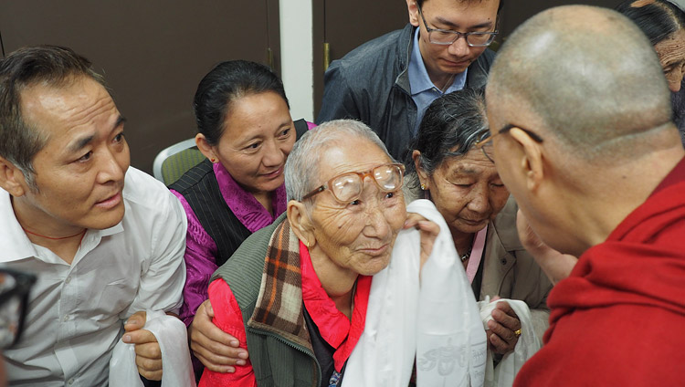 His Holiness the Dalai Lama comforting an elderly Tibetan before his meeting with the Tibetan community in Boston, MA, USA on June 25, 2017. Photo by Jeremy Russell/OHHDL