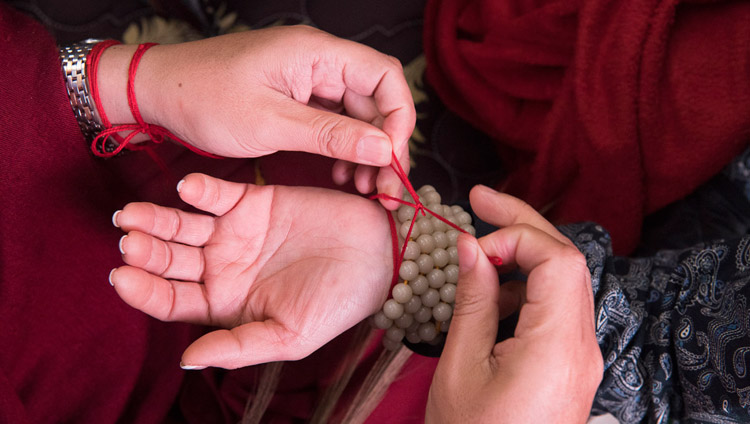 Ritual protection cords being tied to wrists by those attending preparations for the Thirteen Deity Vajrabhairava Empowerment given by His Holiness the Dalai Lama in Bodhgaya, Bihar, India on January 18, 2018. Photo by Manuel Bauer