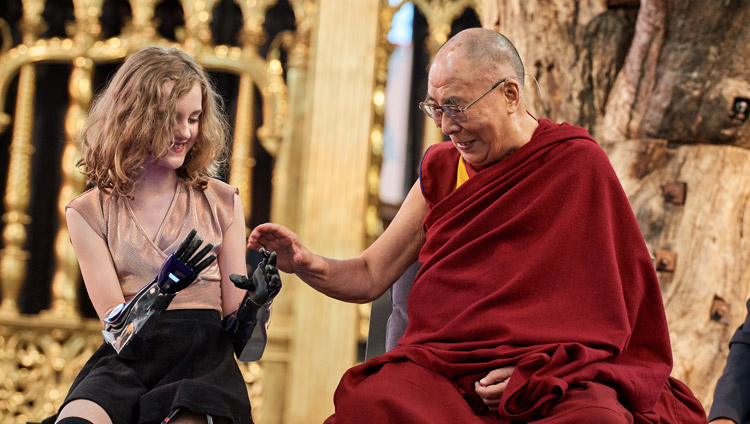 His Holiness the Dalai Lama looking at Tilly Lockey's prosthetic hands during the discussion on ‘Robotics and Telepresence’ at the Nieuwe Kerk in Amsterdam, Netherlands on September 15, 2018. Photo by Olivier Adam