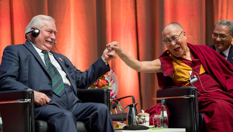 His Holiness the Dala Lama reaching out to clasp the hand of Lech Walesa, leader of the Solidarity movement and former President of Poland, during the discussion on non-violence in Darmstadt, Germany on September 19, 2018. Photo by Manuel Bauer