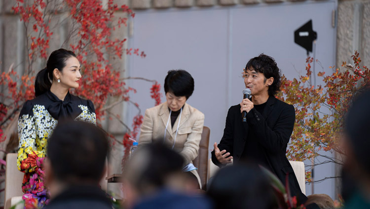 Fashion model Ai Tominaga looks on as film director Kenji Kohashi, both special guests, describes his experiences in Tibet as an introduction to His Holiness the Dalai Lama's talk in Tokyo, Japan on November 17, 2018. Photo by Tenzin Choejor