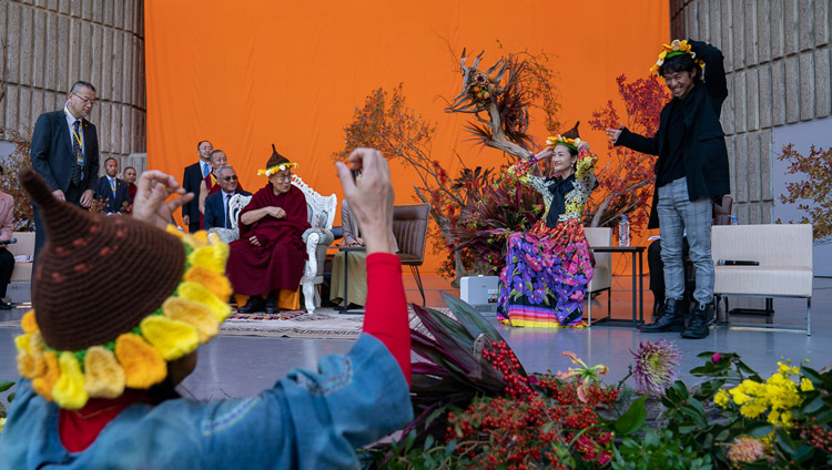 His Holiness the Dalai Lama and two guests wearing knitted sunflower hats presented at the conclusion of his talk "One - We Are One Family" at the Hibiya Open Air Concert Hall in Tokyo, Japan on November 17, 2018.