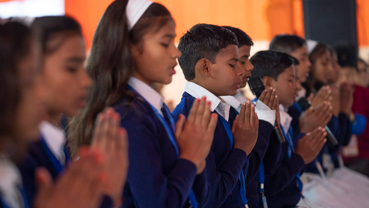 A group of local children in school uniform reciting the Mangala Sutta in Pali at the start of His Holiness the Dalai Lama's teaching in Sankisa, UP, India on December 3, 2018. Photo by Lobsang Tsering