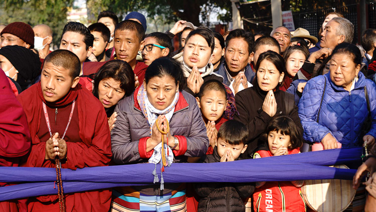 People gathered by the side of the road waiting to catch a glimpse of His Holiness the Dalai Lama as he walks from Gaden Phelgyeling Monastery to the Kalachakra Ground on the second day of his teachings in Bodhgaya, Bihar, India on December 25, 2018. Photo by Lobsang Tsering