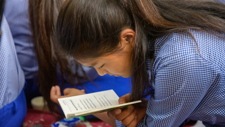 A Tibetan student from Tibetan Children’s Village (TCV) school looking at the text during His Holiness the Dalai Lama's teaching at the Main Tibetan Temple in Dharamsala, HP, India on June 3, 2019. Photo by Tenzin Choejor