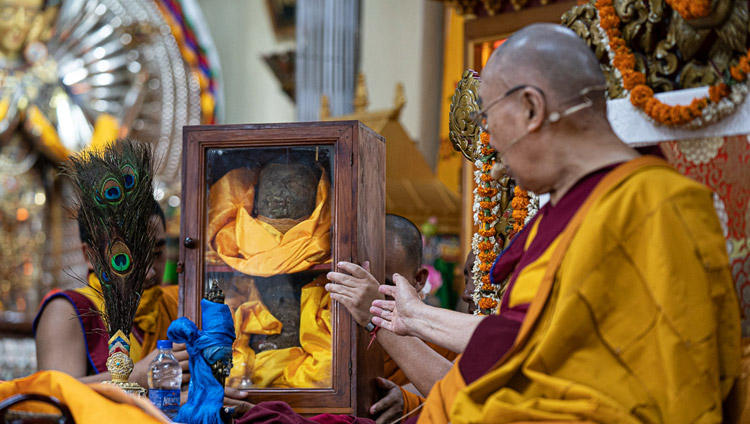 His Holiness the Dalai Lama gesturing at a glass case containing pieces of an Avalokiteshvara statue destroyed during the cultural revolution but later rescued and brought to India as he explains the Avalokiteshvara Empowerment at the Main Tibetan Temple in Dharamsala, HP, India on June 5, 2019. Photo by Tenzin Choejor