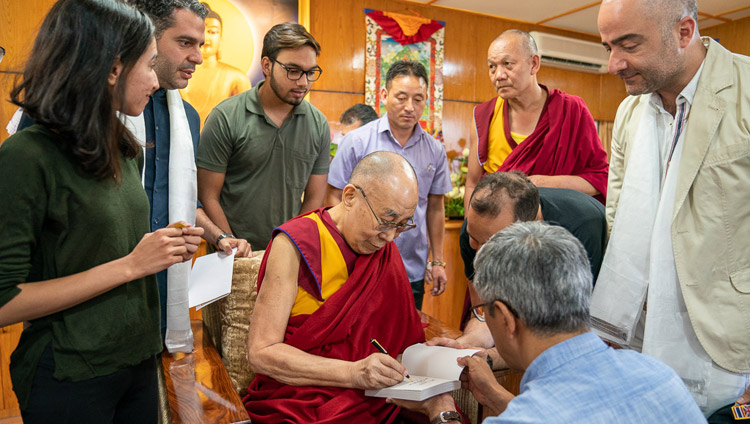 His Holiness the Dalai Lama signing one of his books to present to members of a group from Iran at the conclusion of their meeting at his residence in Dharamsala, HP, India on June 7, 2019. Photo by Tenzin Choejor