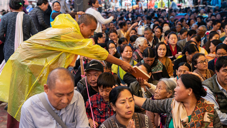 Volunteers handing out books to members of the audience on the second day of His Holiness the Dalai Lama's teachings in Manali, HP, India on August 14, 2019. Photo by Tenzin Choejor