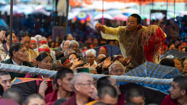 A volunteer passing out ritual protection cords as His Holiness the Dalai Lama gives the Empowerment of Mahakarunika Lokeshvara in Manali, HP, India on August 17, 2019. Photo by Tenzin Choejor