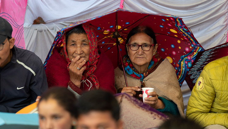 Members of the audience attending His Holiness the Dalai Lama's final day of teachings protecting themselves from the rain in Manali, HP, India on August 18, 2019. Photo by Tenzin Choejor