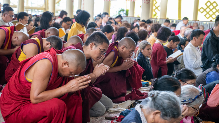 Members of the crowd kneeling as His Holiness the Dalai Lama leads the assembly through the ceremony for generating the awakening mind of bodhichitta on the third day of his teachings at the Main Tibetan Temple in Dharamsala, HP, India on September 6, 2019. Photo by Matteo Passigato