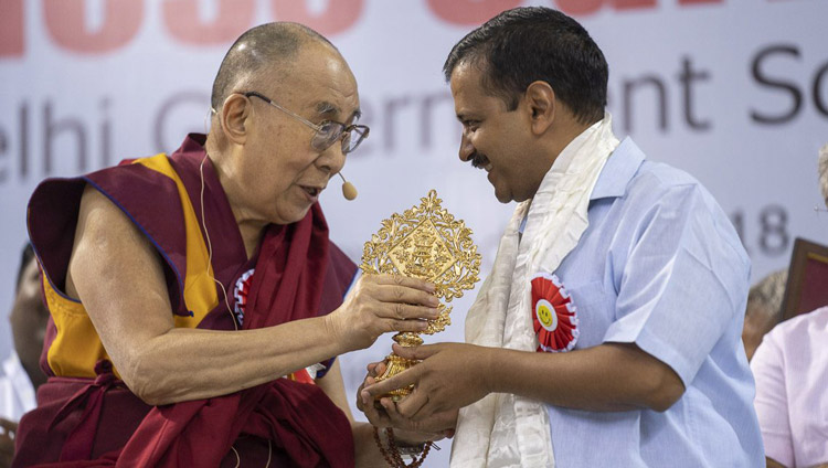 His Holiness the Dalai Lama presenting Delhi Chief Minister Arvind Kejriwal with an auspicious emblem at the conclusion of the launch of the Happiness Curriculum in Delhi Government Schools at Thyagraj Stadium in New Delhi, India on July 2, 2018. Photo by Tenzin Choejor