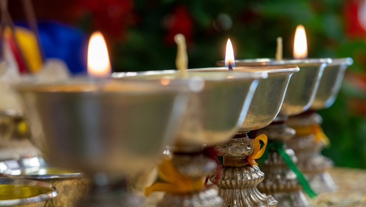 Butter lamps arranged as offerings behind His Holiness the Dalai Lama during the second day of his two day online teaching from his residence in Dharamsala, HP, India on October 10, 2021. Photo by Ven Tenzin Jamphel