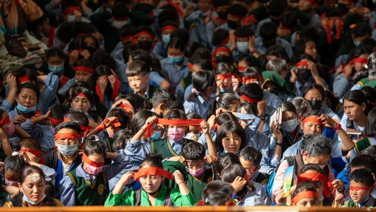 Estudiantes entre la multitud llevando vendas rojas rituales como parte de la iniciación de Avalokiteshvara conferida por Su Santidad el Dalái Lama en el Templo Tibetano Principal en Dharamsala, HP, India, el 2 de junio de 2022. Foto de Tenzin Choejor