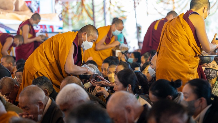 Monks distributing ritual pills to members of the audience during the permission of 21 Taras on the third day of His Holiness the Dalai Lama's teachings at the Kalachakra Teaching Ground in Bodhgaya, Bihar, India on December 31, 2022. Photo by Tenzin Choejor