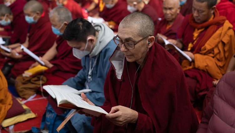 Members of the crowd following along with the text "Commentary on Bodhichitta" by Nagarjuna on the third day of His Holiness the Dalai Lama's teachings at the Kalachakra Teaching Ground in Bodhgaya, Bihar, India on December 31, 2022. Photo by Tenzin Choejor