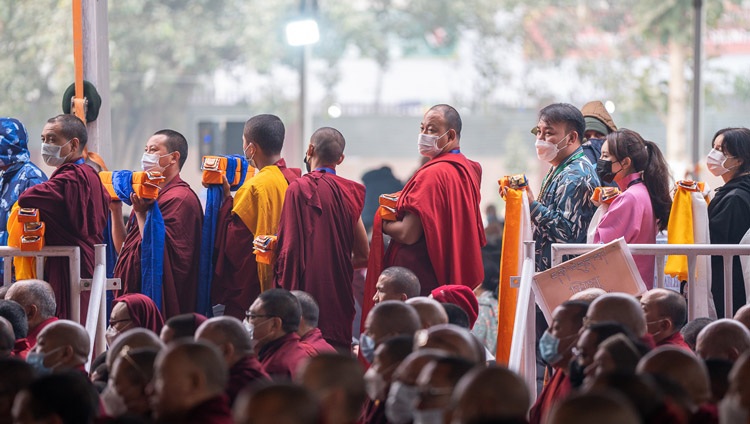 Miembros laicos y mnonásticos de la Tradición Geluk en fila esperando para desfilar delante de Su Santidad el Dalái Lama sosteniendo sus ofrendas durante la oración de larga vida en el Campo de Enseñanza de Kalachakra en Bodhgaya, Bihar, India, el 1 de enero de 2023. Foto de Tenzin Choejor