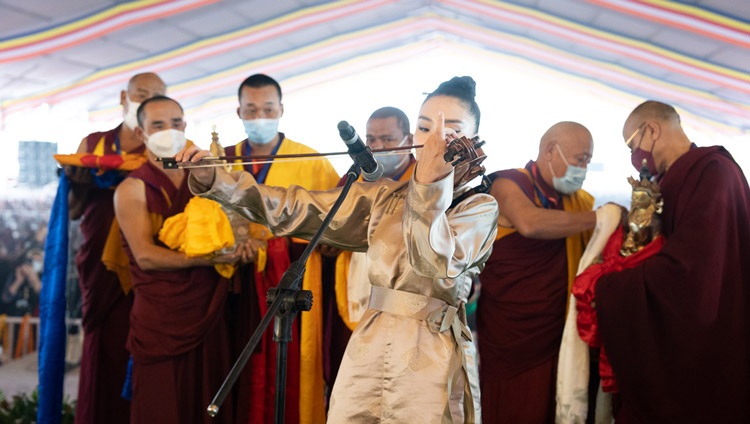 A Mongolian violinist performing as Gaden Tri Rinpoché reads a tribute to His Holiness the Dalai Lama during the Long Life Prayer at the Kalachakra Teaching Ground in Bodhgaya, Bihar, India on January 1, 2023. Photo by Tenzin Choejor