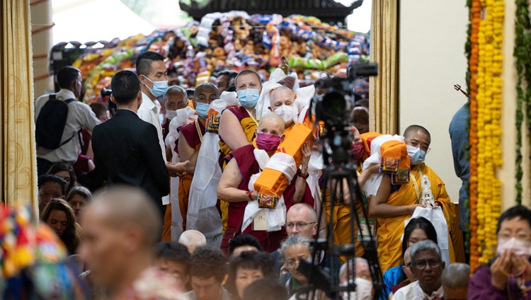 Con el gran montón de ofrendas que iban a ser distribuidas a la multitud como fondo, los miembros de la Fundación para la preservación de la tradición Mahayana (FPMT) se alinearon a la entrada del templo tibetano principal con ofrendas para entregar a Su Santidad el Dalái Lama durante la ceremonia de ofrenda de larga vida en Dharamsala, HP, India, el 24 de mayo de 2023. Foto de Tenzin Choejor