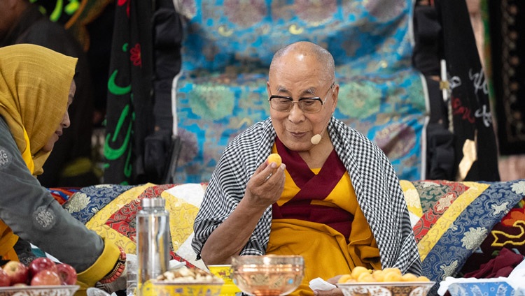 Su Santidad el Dalái Lama a punto de tomar un bocado de albaricoque durante su charla a los miembros de la comunidad musulmana en Imam Bargah, Chuchot Yokma, en Leh, Ladakh, India, el 12 de agosto de 2023. Foto de Tenzin Choejor