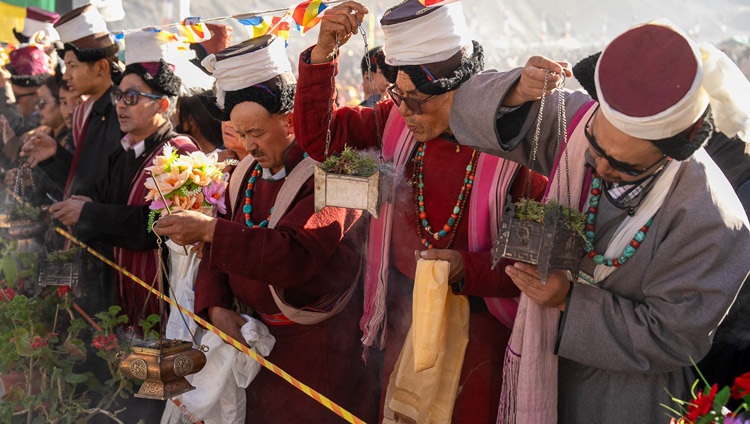 Miembros de la multitud alineados en la carretera sosteniendo flores y quemando incienso esperan para dar la bienvenida a Su Santidad el Dalái Lama a su llegada al terreno de enseñanzas en Khaltse, Ladakh, India, el 19 de agosto de 2023. Foto de Tenzin Choejor