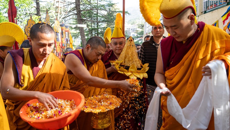 Monks scattering flower petals lead the way as the relics of the Buddha are carried up the drive of the Main Tibetan Temple to offer to His Holiness the Dalai Lama waiting at the gate to his residence in Dharamsala, HP, India on April 4, 2024. Photo by Tenzin Choejor 